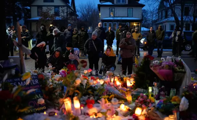 People gather around a makeshift memorial honoring Renee Good, who was fatally shot by an ICE officer the day before, near the site of the shooting in Minneapolis, Thursday, Jan. 8, 2026. (AP Photo/John Locher)