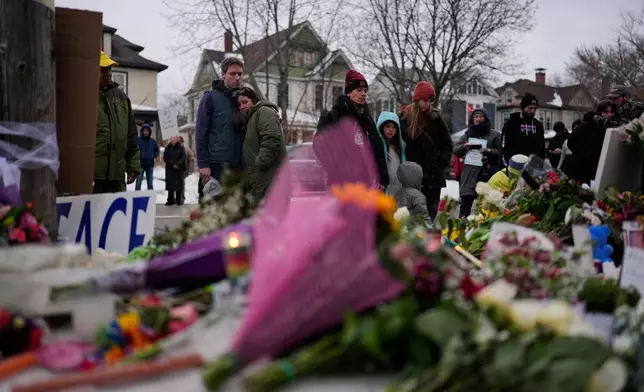 People gather around a makeshift memorial honoring Renee Good, who was fatally shot by an ICE officer the day before, near the site of the shooting in Minneapolis, Thursday, Jan. 8, 2026. (AP Photo/John Locher)