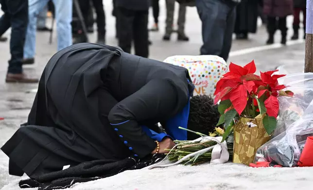 A person kneels to the ground at the makeshift memorial honoring the victim of a fatal shooting involving federal law enforcement agents, near the site of the shooting, Thursday, Jan. 8, 2026, in Minneapolis. (AP Photo/Tom Baker)