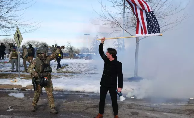 A supporter of United States Immigration and Customs Enforcement holds a flag outside the Bishop Henry Whipple Federal Building in Minneapolis, Friday, Jan. 9, 2026. (AP Photo/Adam Bettcher)