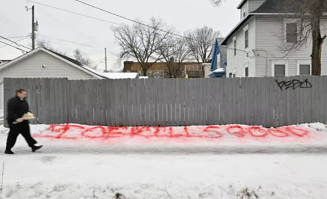 A person walks by writing in the snow near a makeshift memorial honoring the victim of a fatal shooting involving federal law enforcement agents, near the site of the shooting, Thursday, Jan. 8, 2026, in Minneapolis. (AP Photo/Tom Baker)