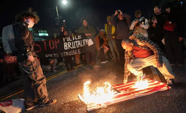 A protester burns an American flag in front of the Metropolitan Detention Center for the Federal Bureau of Prisons during a protest in Los Angeles, Thursday, Jan. 8, 2026, following the death of Renee Good, who was fatally shot by an ICE officer. (AP Photo/Jae C. Hong)