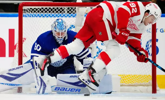 Toronto Maple Leafs goaltender Joseph Woll (60) makes a save as Detroit Red Wings' Marco Kasper (92) stumbles during second period NHL hockey action in Toronto on Wednesday, Jan. 21, 2026. (Frank Gunn/The Canadian Press via AP)