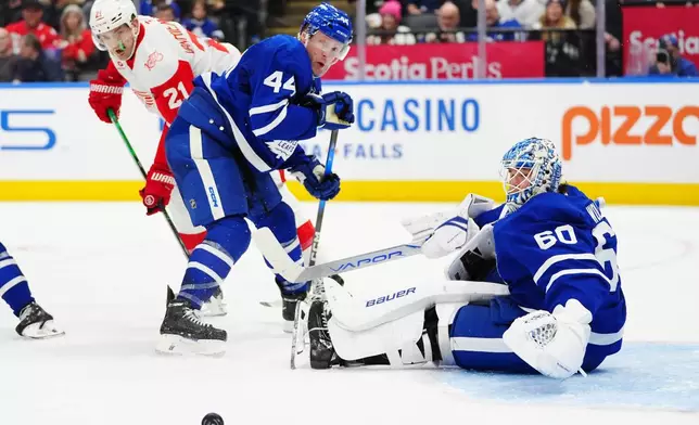 Toronto Maple Leafs goaltender Joseph Woll (60) makes a save as Morgan Rielly (44) battles with Detroit Red Wings' James van Riemsdyk (21) during the third period of an NHL hockey game in Toronto, Wednesday, Jan. 21, 2026. (Frank Gunn/The Canadian Press via AP)