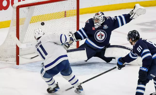Toronto Maple Leafs' Max Domi (11) scores the game-winning overtime goal against Winnipeg Jets goaltender Connor Hellebuyck (37) during NHL action in Winnipeg, Saturday, Jan. 17, 2026. (John Woods/The Canadian Press via AP)
