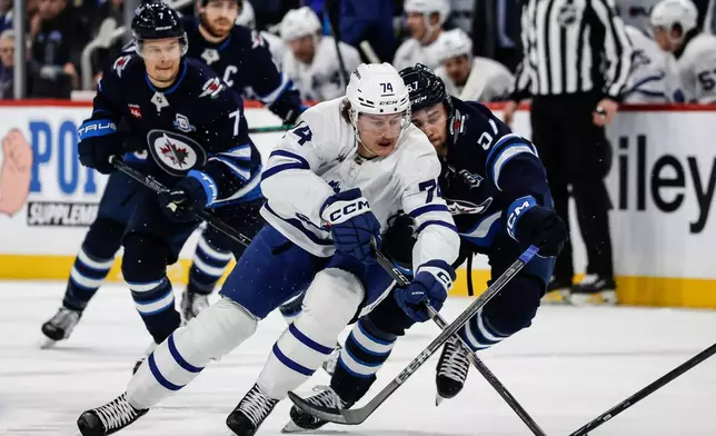 Winnipeg Jets' Elias Salomonsson (57) defends against Toronto Maple Leafs' Bobby McMann (74) who breaks toward the net during first-period NHL hockey game action in Winnipeg, Manitoba, Saturday, Jan. 17, 2026. (John Woods/The Canadian Press via AP)