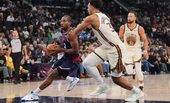 Los Angeles Clippers forward Kawhi Leonard (2) drives past Golden State Warriors forward Trayce Jackson-Davis (32) as Warriors guard Stephen Curry (30) watches during the first half of an NBA basketball game Monday, Jan. 5, 2026, in Inglewood, Calif. (AP Photo/Jae C. Hong)