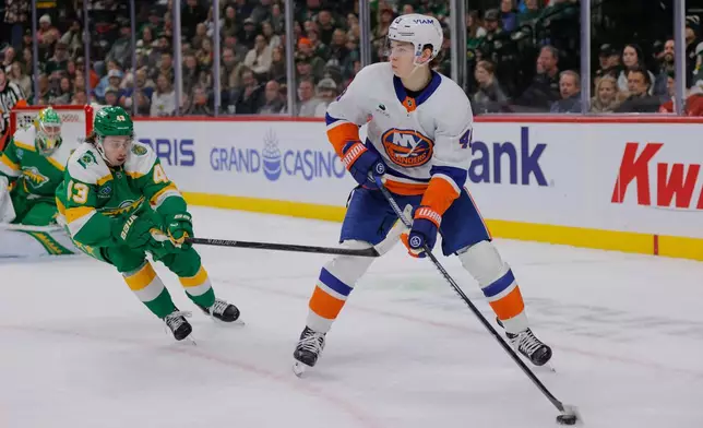 New York Islanders defenseman Matthew Schaefer (48) skates with the puck as Minnesota Wild defenseman Quinn Hughes (43) defends during the first period of an NHL hockey game Saturday, Jan. 10, 2026, in St. Paul, Minn. (AP Photo/Bailey Hillesheim)