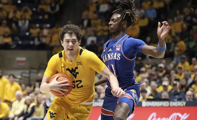 West Virginia guard Treysen Eaglestaff (52) is defended by Kansas guard Jamari McDowell (11) during the first half of an NCAA college basketball game Saturday, Jan. 10, 2026, in Morgantown, W.Va. (AP Photo/Kathleen Batten)
