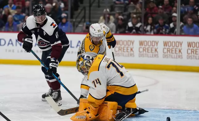 Colorado Avalanche center Brock Nelson, left, shoots past Nashville Predators goaltender Juuse Saros (74) and defenseman Nick Blankenburg (37) for a goal in the first period of an NHL hockey game Friday, Jan. 16, 2026, in Denver. (AP Photo/David Zalubowski)