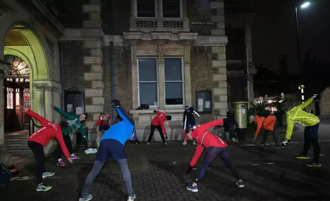 Participants in the Goodgym group warm up before running to collect litter to keep the River Thames free of plastic and other waste in London, Wednesday, Jan. 14, 2026. (AP Photo/Kirsty Wigglesworth)