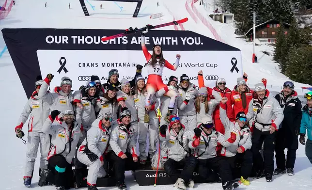 Switzerland's Malorie Blanc, center, celebrates on the podium with the team after winning an alpine ski, women's World Cup Super G, in Crans Montana, Switzerland, Saturday, Jan. 31, 2026. (AP Photo/Giovanni Auletta)