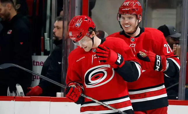 Carolina Hurricanes' Alexander Nikishin (21) picks on Joel Nystrom (64) after Nystrom scored his first NHL goal against the Chicago Blackhawks during the first period of an NHL hockey game in Raleigh, N.C., Thursday, Jan. 22, 2026. (AP Photo/Karl DeBlaker)