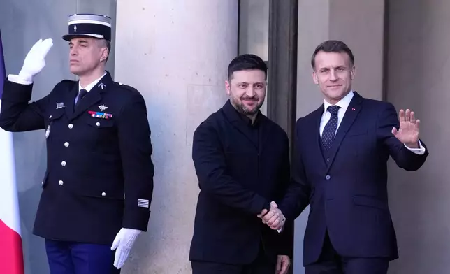 Ukraine's President Volodymyr Zelenskyy, center, is greeted by French President Emmanuel Macron, right, as he arrives for a meeting of the 'Coalition of the Willing' on Ukraine at the Elysee Palace in Paris, France, Tuesday, Jan. 6, 2026. (AP Photo/Michel Euler)