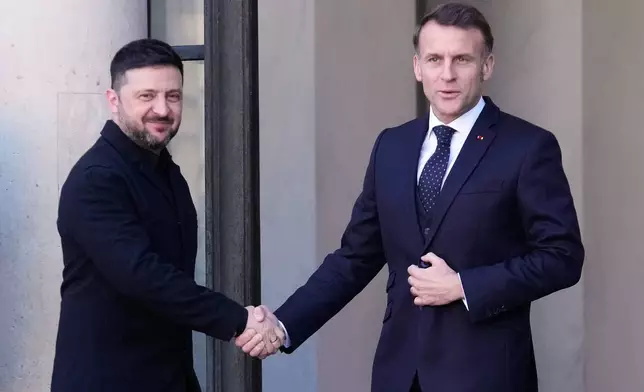 Ukraine's President Volodymyr Zelenskyy, left, is greeted by French President Emmanuel Macron as he arrives for a meeting of the 'Coalition of the Willing' on Ukraine at the Elysee Palace in Paris, France, Tuesday, Jan. 6, 2026. (AP Photo/Michel Euler)