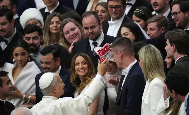 Pope Leo XIV is handed a package of Peeps marshmallow candy as he meets faithful at the end of his weekly general audience in the Paul VI Hall at the Vatican, Wednesday, Jan. 7, 2026. (AP Photo/Alessandra Tarantino)