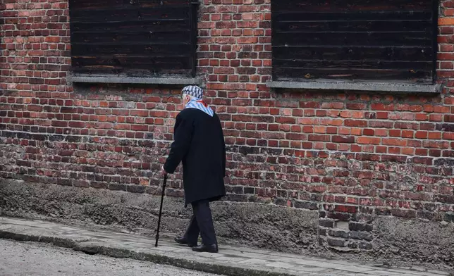 Holocaust survivor Stanislaw Zalewski walks along a wall in the Auschwitz Nazi death camp museum during a ceremony marking the 81th anniversary of the camp's liberation in Oswiecim, Poland, Tuesday, Jan. 27, 2026. (AP Photo/Beata Zawrzel)