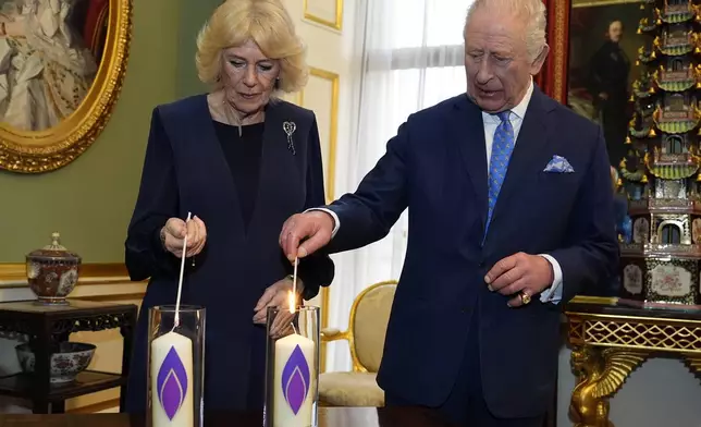 Britain's King Charles III and Queen Camilla, left, light candles during a reception at Buckingham Palace to mark Holocaust Memorial Day, in London, Tuesday, Jan. 27, 2026. (Aaron Chown/Pool Photo via AP)