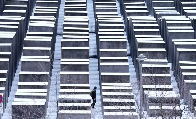 A man walks through the snow covered Holocaust memorial on the International Holocaust Memorial Day in Berlin, Germany, Tuesday, Jan. 27, 2026. (AP Photo/Markus Schreiber)
