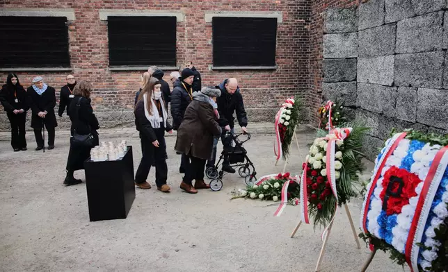 Holocaust survivors lay flowers at the death wall in the Auschwitz Nazi death camp museum during a ceremony marking the 81th anniversary of the camp's liberation in Oswiecim, Poland, Tuesday, Jan. 27, 2026. (AP Photo/Beata Zawrzel)