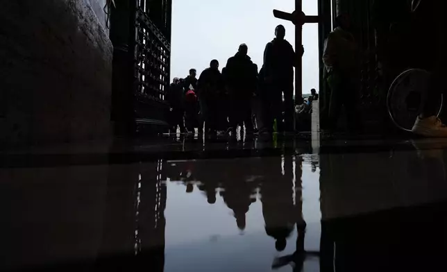 Pilgrims and faithful hold a crucifix as they arrive to St. Peter's Basilica at the Vatican to cross the Holy Door on the last day of its public opening, Monday, Jan. 5, 2026. (AP Photo/Alessandra Tarantino)