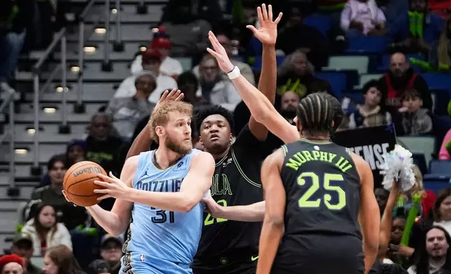 Memphis Grizzlies center Jock Landale (31) looks to pass around New Orleans Pelicans center Derik Queen (22) and forward Trey Murphy III (25) in the first half of an NBA basketball game, Friday, Jan. 30, 2026, in New Orleans. (AP Photo/Gerald Herbert)
