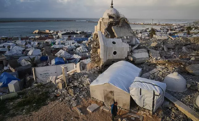 A man walks through tents sheltering displaced Palestinians amid the ruins left by the Israeli air and ground offensive in Gaza City, Wednesday, Jan. 28, 2026. (AP Photo/Jehad Alshrafi)