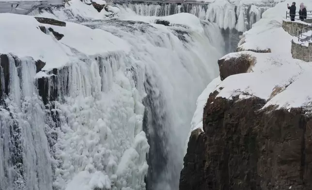 People look over the partial frozen Great Falls in Paterson, N.J., Wednesday, Jan. 28, 2026. (AP Photo/Seth Wenig)