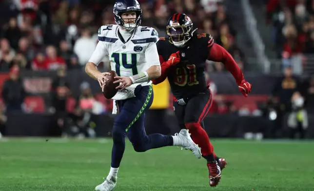 Seattle Seahawks quarterback Sam Darnold (14) rolls out to pass while pressured by San Francisco 49ers defensive tackle Sam Okuayinonu (91) during the second half of an NFL football game in Santa Clara, Calif., Saturday, Jan. 3, 2026. (AP Photo/Jed Jacobsohn)