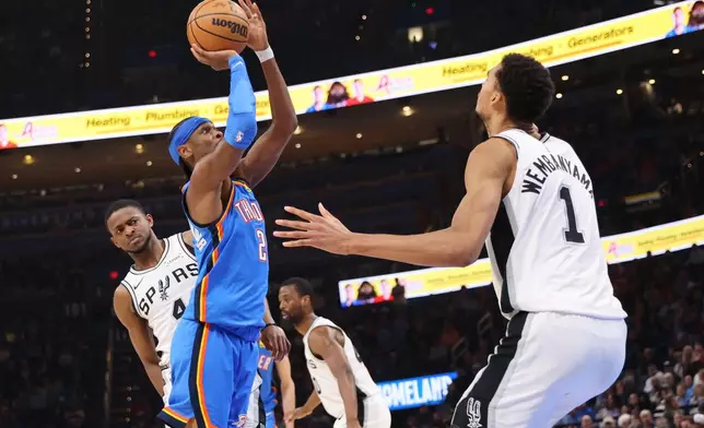 Oklahoma City Thunder guard Shai Gilgeous-Alexander (2) looks to shoot between San Antonio Spurs guard De'aaron Fox, left, and forward Victor Wembanyama (1) during the second half of an NBA basketball game Tuesday, Jan. 13, 2026, in Oklahoma City. (AP Photo/Nate Billings)