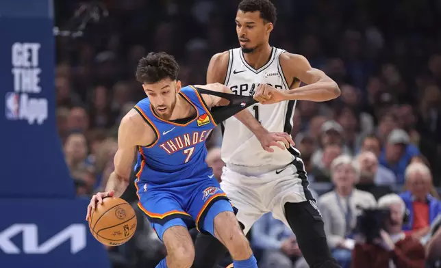 San Antonio Spurs forward Victor Wembanyama (1) holds the shirt of Oklahoma City Thunder center Chet Holmgren (7) during the first half of an NBA basketball game Tuesday, Jan. 13, 2026, in Oklahoma City. (AP Photo/Nate Billings)