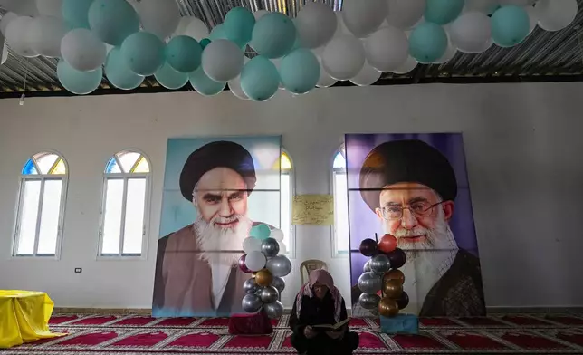 A Syrian Shiite man reads the holy book of Quran in front of portraits of Iranian Supreme Leader Ayatollah Ali Khamenei, right, and the late Iranian revolutionary founder Ayatollah Khomeini, left, at the Imam Ali Housing Compound, where hundreds of mostly Lebanese and Syrian Shiite Muslims displaced from Syria reside, in Hermel, northeast Lebanon, Friday, Jan. 30, 2026. (AP Photo/Hussein Malla)