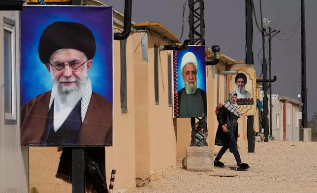 A Syrian Shiite woman walks next of portraits of Iranian Supreme Leader Ayatollah Ali Khamenei, foreground, Hezbollah leader Sheikh Naim Kassem, centre, and the late Hezbollah leader Sayyed Hassan Nasrallah, background, at the Imam Ali Housing Compound, where hundreds of mostly Lebanese and Syrian Shiite Muslims displaced from Syria reside, in Hermel, northeast Lebanon, Friday, Jan. 30, 2026. (AP Photo/Hussein Malla)