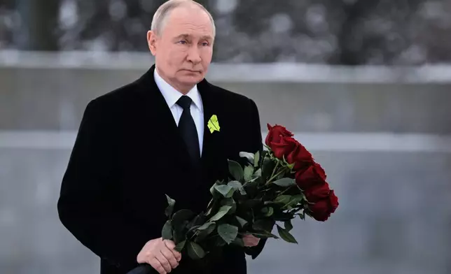 Russian President Vladimir Putin lays flowers at the grave of his brother, who died as a child during the siege of Leningrad, during a commemoration ceremony at the Piskaryovskoye Cemetery, where most of the Leningrad Siege victims were buried, marking the 82nd anniversary of the World War II battle that lifted the Nazi siege of Leningrad, in St. Petersburg, Russia, Tuesday, Jan. 27, 2026. (Alexei Danichev/Sputnik, Kremlin Pool Photo via AP)