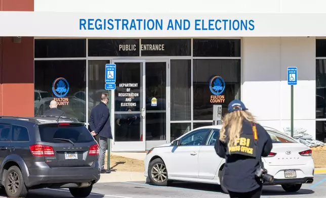 An FBI press office person approaches the Fulton County Election Hub and Operation Center, Wednesday, Jan. 28, 2026, in Union City, Ga. (Arvin Temka/Atlanta Journal-Constitution via AP)