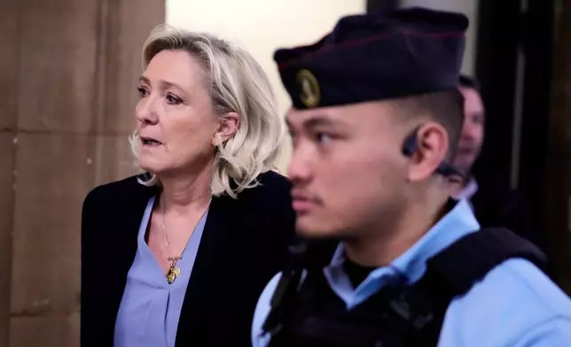 Far-right leader Marine Le Pen, left, walks outside the courtroom during a short break in her appeals trial in Paris, Tuesday, Jan. 20, 2026. (AP Photo/Michel Euler)
