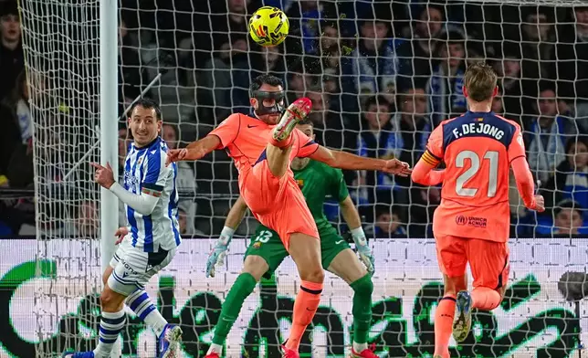 Barcelona's Eric Garcia, centre, kicks the ball ahead of Real Sociedad's Mikel Oyarzabal, left, and Barcelona's Frenkie de Jong during the Spanish La Liga soccer match between Real Sociedad and Barcelona in San Sebastian, Spain, Sunday, Jan. 18, 2026. (AP Photo/Miguel Oses)
