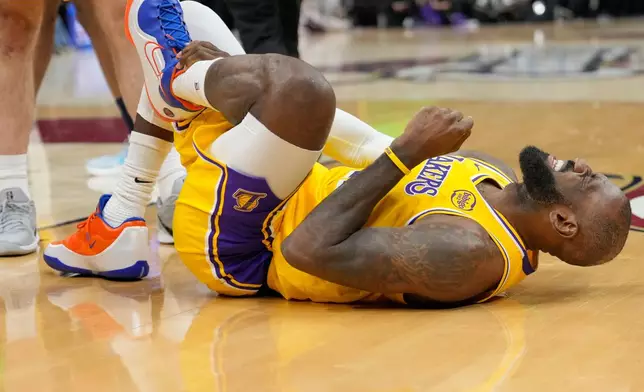Los Angeles Lakers forward LeBron James grimaces after a fall in the second half of an NBA basketball game against the Cleveland Cavaliers in Cleveland, Wednesday, Jan. 28, 2026. (AP Photo/Sue Ogrocki)