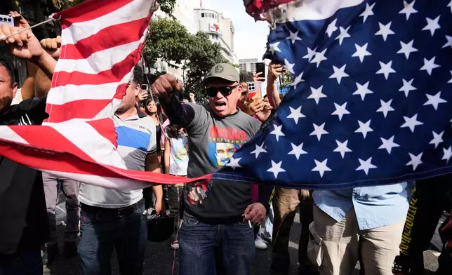 Government supporters rip an American flag in half during a protest in Caracas, Venezuela, Saturday, Jan. 3, 2026, after U.S. President Donald Trump announced that U.S. forces had captured President Nicolás Maduro and first lady Cilia Flores. (AP Photo/Ariana Cubillos)