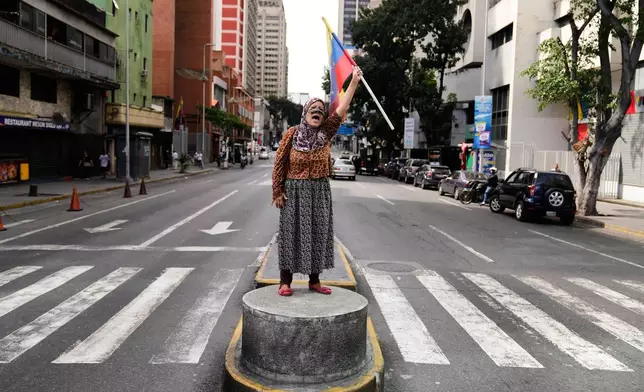 A supporter of Venezuelan President Nicolas Maduro stands on a median strip waving a national flag in Caracas, Venezuela, Saturday, Jan. 3, 2026, after U.S. President Donald Trump announced that Maduro had been captured and flown out of the country. (AP Photo/Ariana Cubillos)
