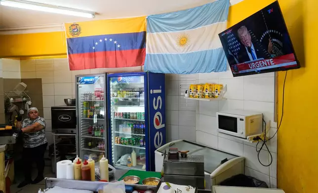 A Venezuelan national watches a live televised broadcast of U.S. President Donald Trump speaking at a press conference about the capture of President Nicolas Maduro, at a Venezuelan restaurant in Buenos Aires, Argentina, Saturday, Jan. 3, 2026. (AP Photo/Natacha Pisarenko)