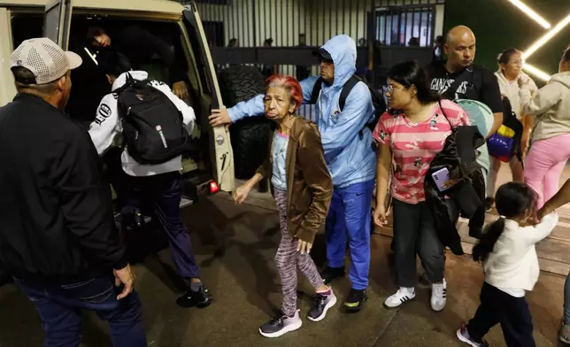 Residents evacuate a building near the Miraflores presidential palace after explosions and low-flying aircraft were heard in Caracas, Venezuela, Saturday, Jan. 3, 2026. (AP Photo/Cristian Hernandez)
