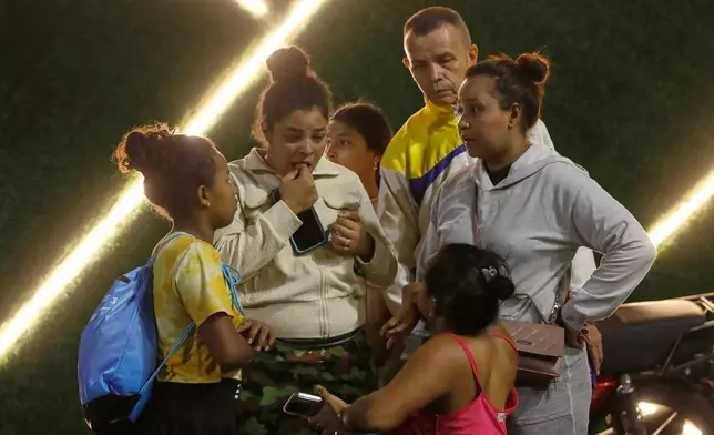 Residents evacuate a building near the Miraflores presidential palace after explosions and low-flying aircraft were heard in Caracas, Venezuela, Saturday, Jan. 3, 2026. (AP Photo/Cristian Hernandez)