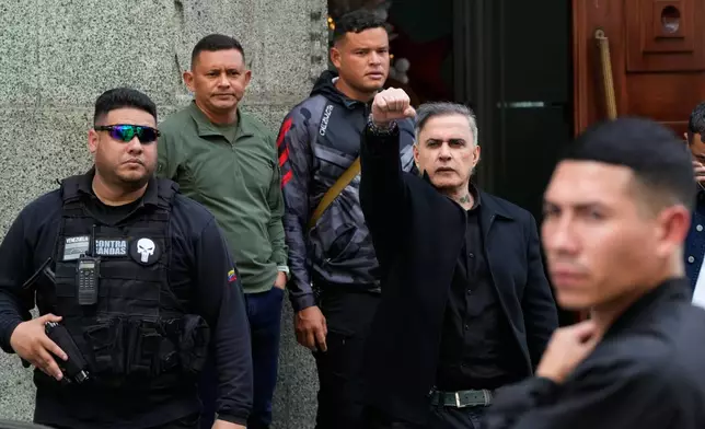 Attorney General Tarek William Saab raises his right fist as he leaves the vice president's office in Caracas, Venezuela, Saturday, Jan. 3, 2026. (AP Photo/Ariana Cubillos)