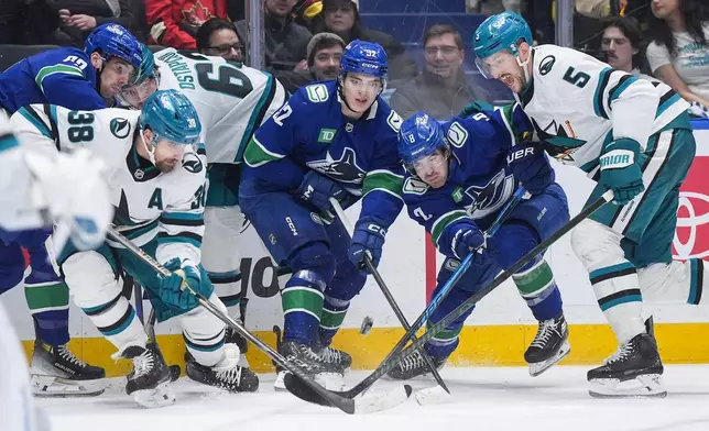 Vancouver Canucks' Conor Garland (8), Liam Ohgren (92) and Filip Chytil (72) vie for the puck against San Jose Sharks' Vincent Desharnais (5), Mario Ferraro (38) and Zack Ostapchuk (63) during the third period of an NHL hockey game, in Vancouver, British Columbia, Tuesday, Jan. 27, 2026. (Darryl Dyck/The Canadian Press via AP)