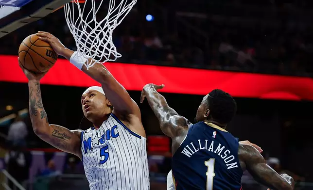 Orlando Magic forward Paolo Banchero (5) goes up to shoot as he is defended by New Orleans Pelicans forward Zion Williamson (1) during the second half of an NBA basketball game Sunday, Jan. 11, 2026, in Orlando, Fla. (AP Photo/Kevin Kolczynski)