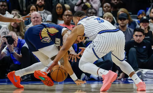 New Orleans Pelicans guard Jordan Poole, left, and Orlando Magic guard Desmond Bane (3) go for a loose ball during the first half of an NBA basketball game, Sunday, Jan. 11, 2026, in Orlando, Fla. (AP Photo/Kevin Kolczynski)