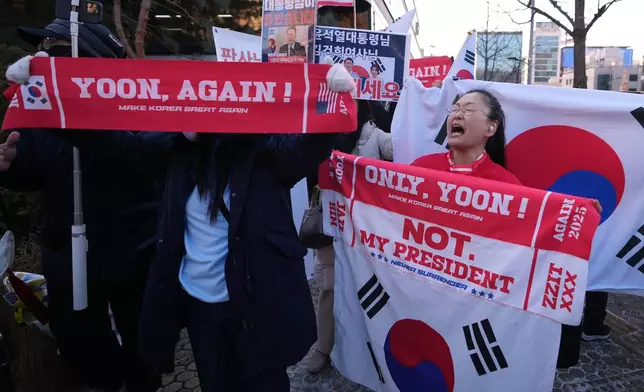 Supporters of former South Korean President Yoon Suk Yeol hold signs outside of Seoul Central District Court, in Seoul, South Korea, Tuesday, Jan. 13, 2026. (AP Photo/Lee Jin-man)