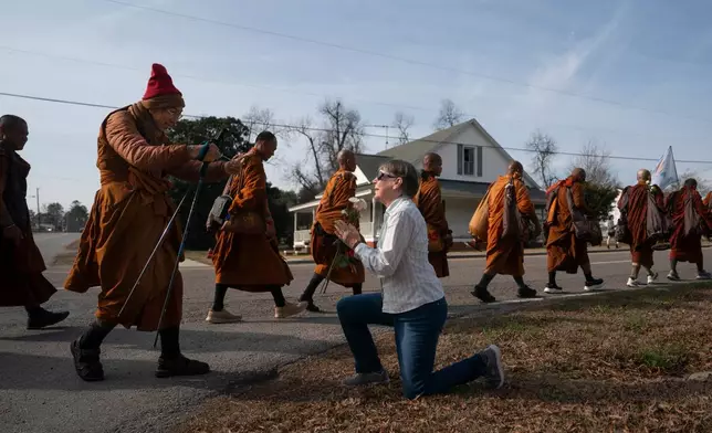 Audrie Pearce greets Buddhist monks who are participating in the, "Walk For Peace," Thursday, Jan. 8, 2026, in Saluda, S.C. (AP Photo/Allison Joyce)