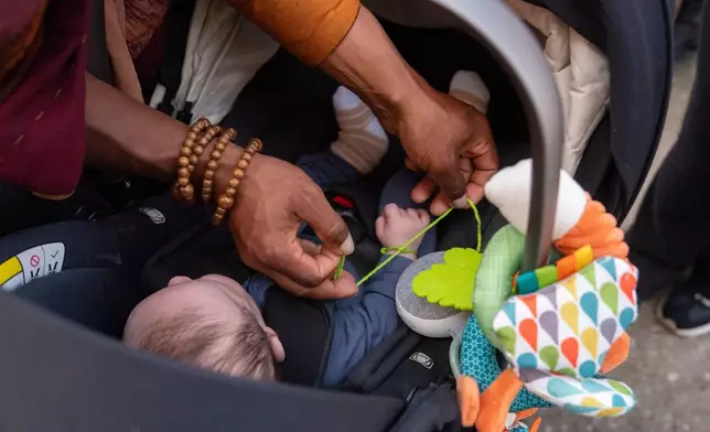A Buddhist monk ties a prayer bracelet around the wrist of Josey Lee, 2-months-old, during the, "Walk For Peace," Thursday, Jan. 8, 2026, in Saluda, S.C. (AP Photo/Allison Joyce)